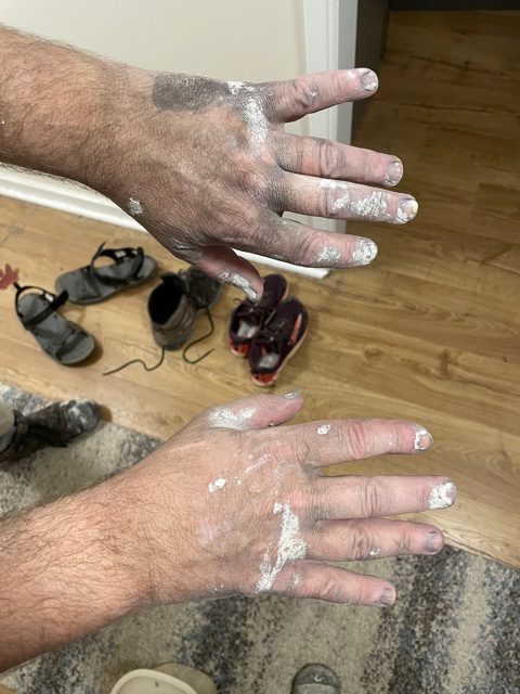 Photo of two hands covered in drywall mud