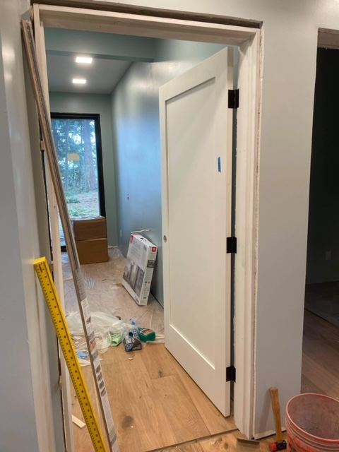 Open white door leading to guest suite with construction materials