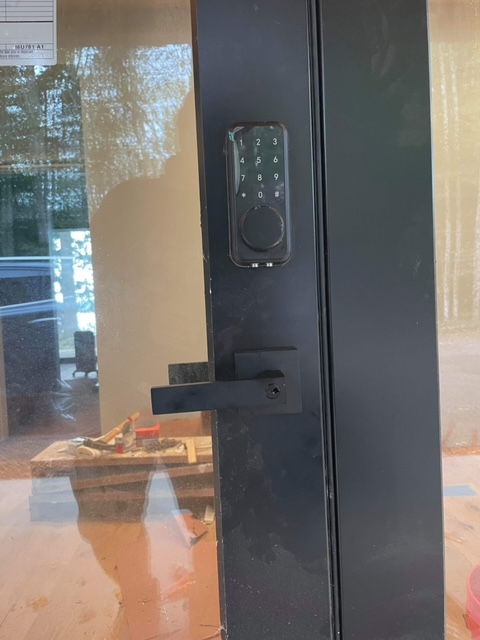 Black combination lock and door handle on black frame with glass insert
