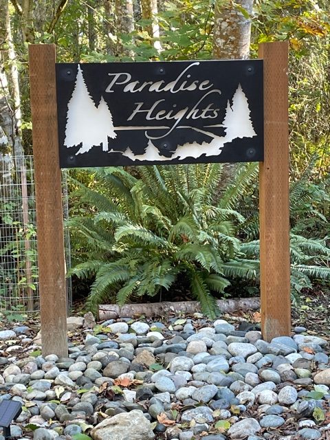 "Paradise Heights" black sign with white backing on wooden posts