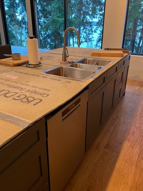 Large kitchen island with sink, faucet, and dishwasher visible