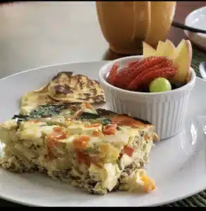 Egg frittata with fruit in a ramekin on a white plan on a cement table